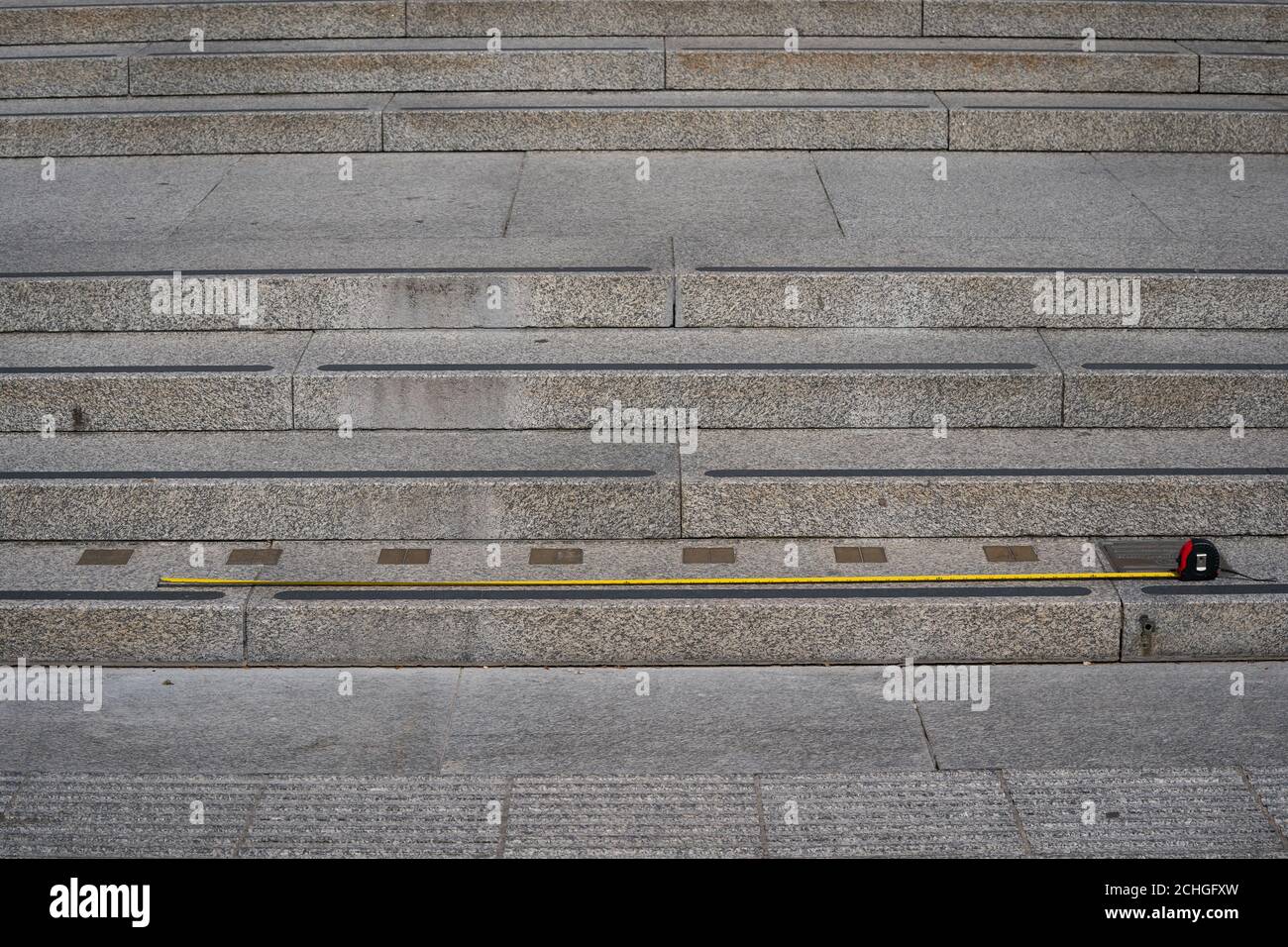 A tape measure is placed against the Imperial measurement markers embedded on the steps leading up to the National Portrait Gallery at Trafalgar Square in London as the UK continues in lockdown to help curb the spread of the coronavirus. Stock Photo