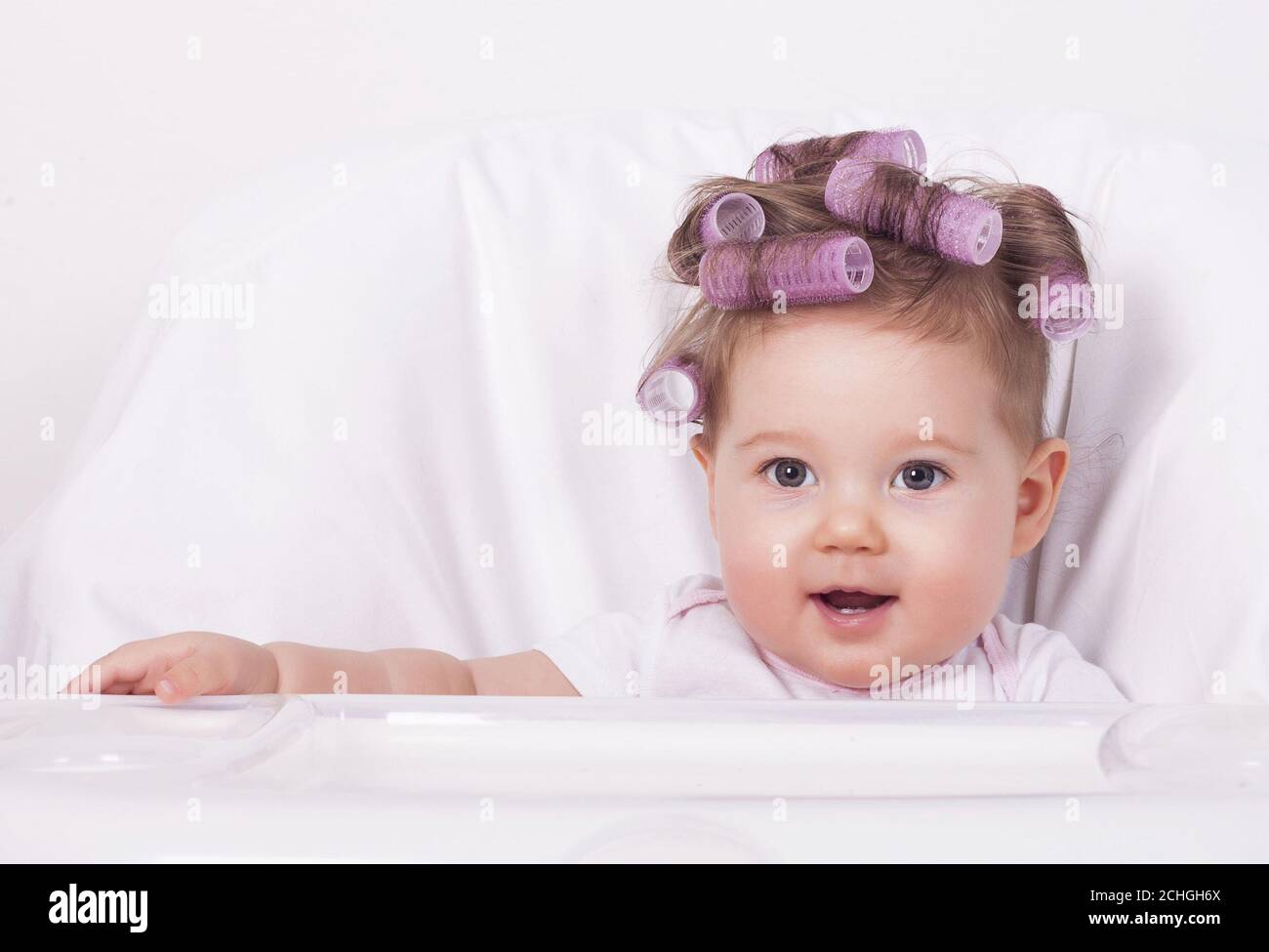 Cute baby girl with plastic hair rollers Stock Photo