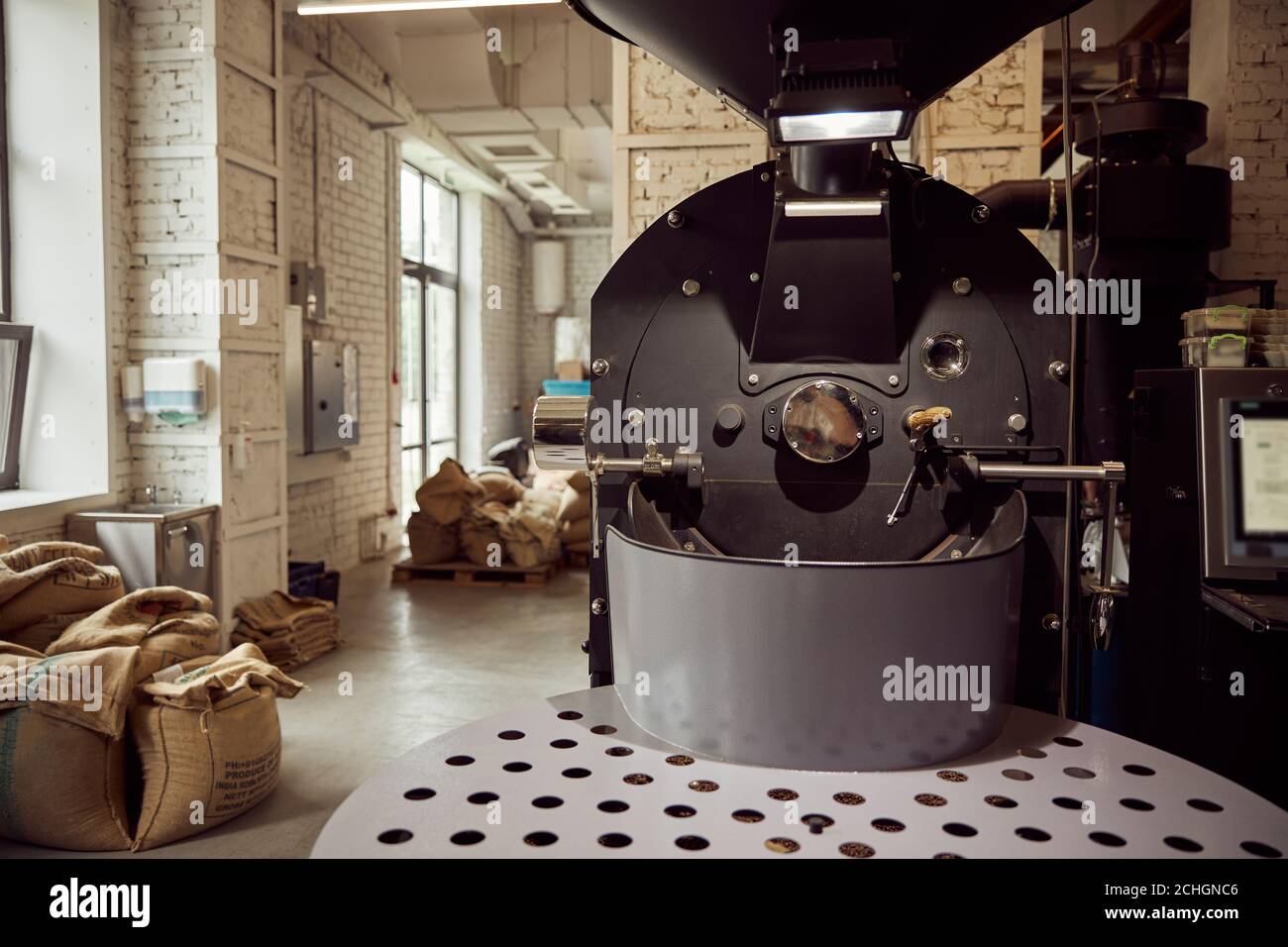 Coffee roasting machine and coffee beans in bags Stock Photo Alamy