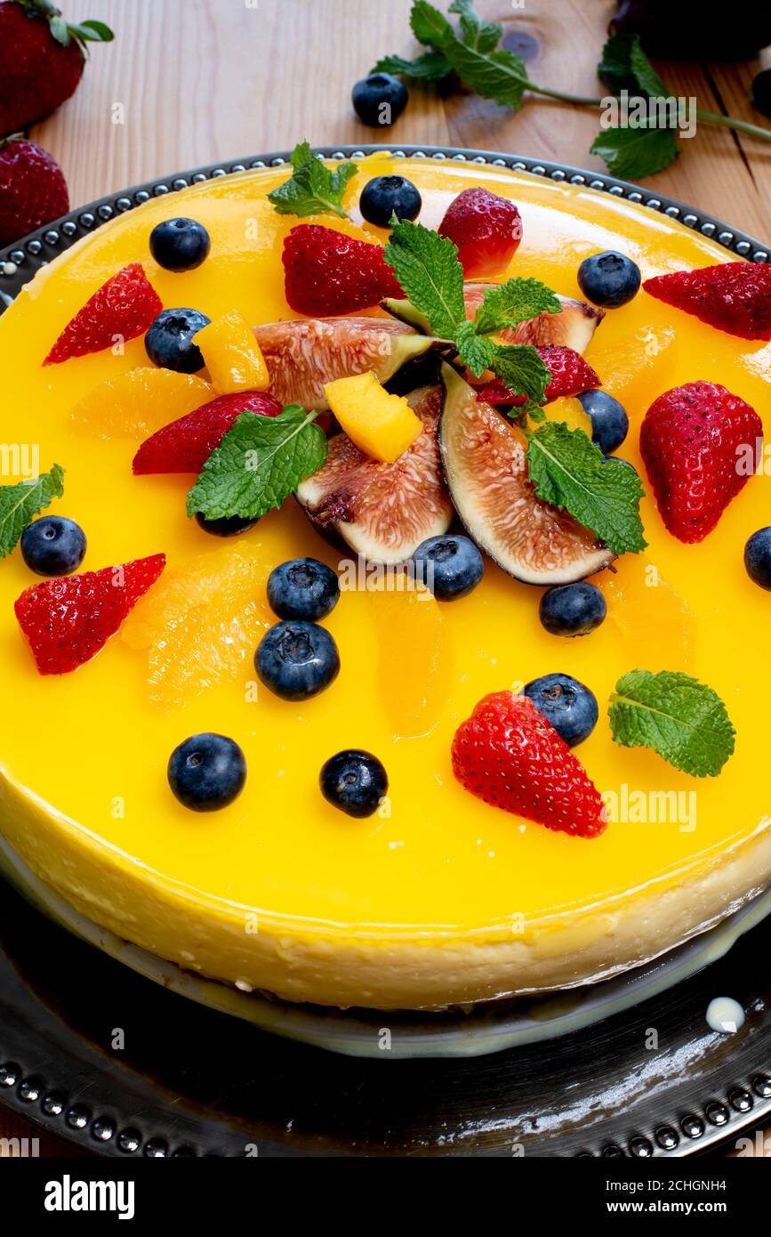Delicious orange cheesecake decorated with fruits and mint leaves Stock Photo