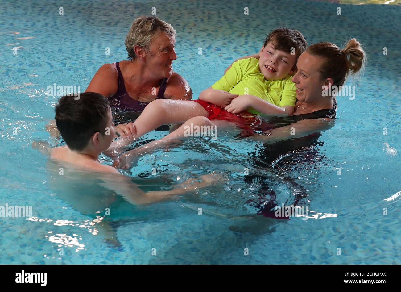 Embargoed to 0001 Monday June 22 Early Years Practitoner Carole King (left) alongside Nicola Devlin with her sons Sean Kearns and Evan (back to camera) as they take part in Parent-led aquatic therapy in the Hydrotherapy pool at the Craighalbert Centre. Coronavirus adaptations have been installed at the Scottish Centre for Children with Motor Impairments, Craighalbert Centre, Cumbernauld, as Scotland continues gradually lifting coronavirus lockdown measures. Stock Photo