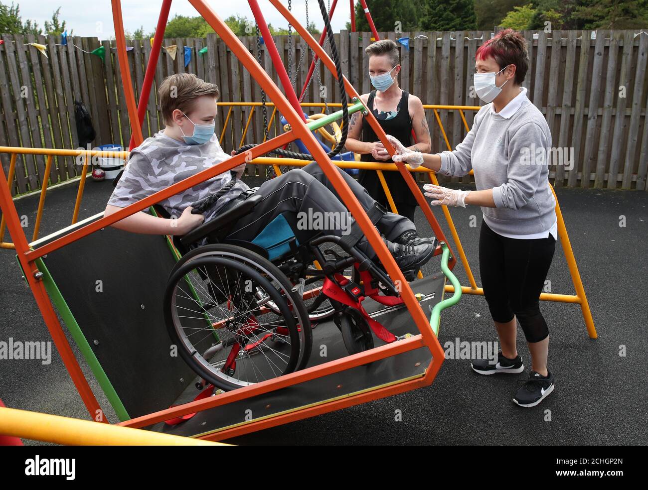 Embargoed to 0001 Monday June 22 Gregor Marshall with his mum Karen alongside Early Years Practitioner Catherine Anderson (right) as Gregor has a ride on the wheelchair swing in the outside therapy area at the Craighalbert Centre. Coronavirus adaptations have been installed at the Scottish Centre for Children with Motor Impairments, Craighalbert Centre, Cumbernauld, as Scotland continues gradually lifting coronavirus lockdown measures. Stock Photo
