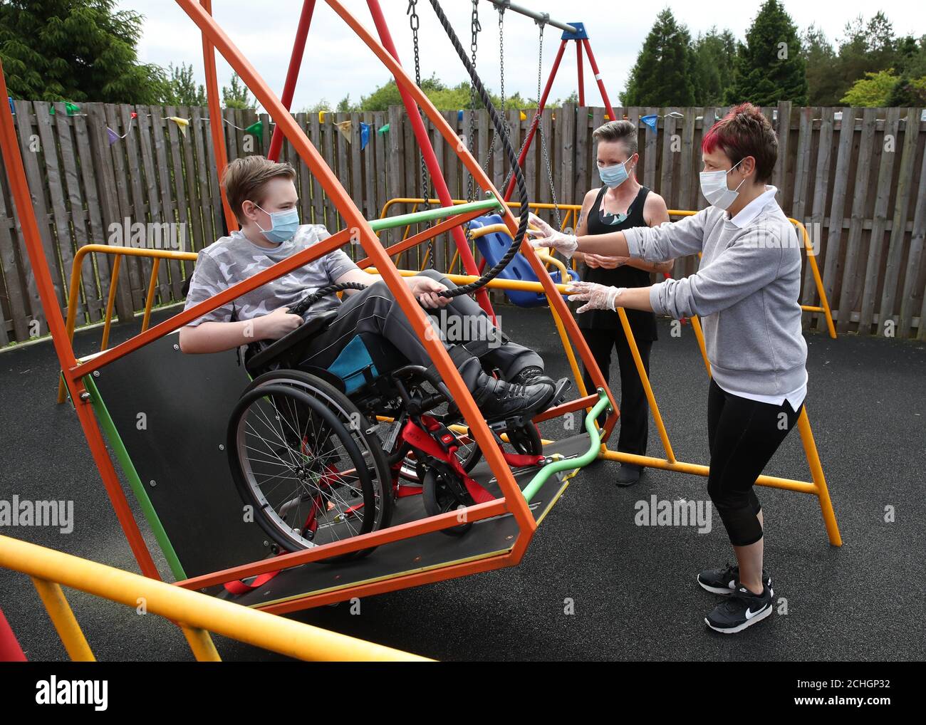 Embargoed to 0001 Monday June 22 Gregor Marshall with his mum Karen alongside Early Years Practitioner Catherine Anderson (right) as Gregor has a ride on the wheelchair swing in the outside therapy area at the Craighalbert Centre. Coronavirus adaptations have been installed at the Scottish Centre for Children with Motor Impairments, Craighalbert Centre, Cumbernauld, as Scotland continues gradually lifting coronavirus lockdown measures. Stock Photo