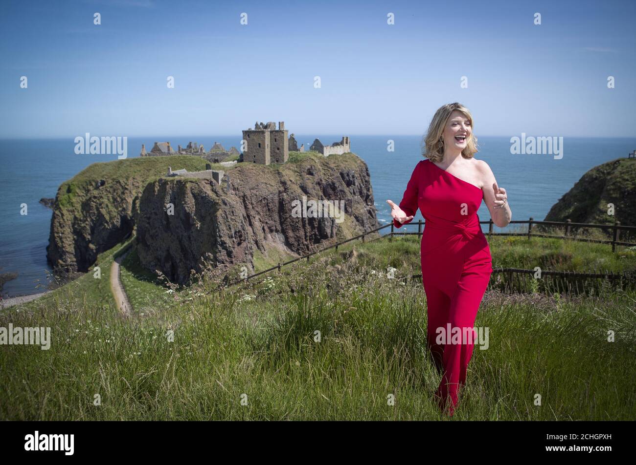 EMBARGOED TO 0001 MONDAY JUNE 29 Scottish singer, song-writer and broadcaster Fiona Kennedy sings 'Stronger for the Storm', a new international song of peace, on the clifftop overlooking Dunnottar Castle on the Aberdeenshire coast, at the launch of iSing4Peace on the anniversary of the signing of the Treaty of Versailles which brought an official end to the First World War and restored peace to the world. Stock Photo