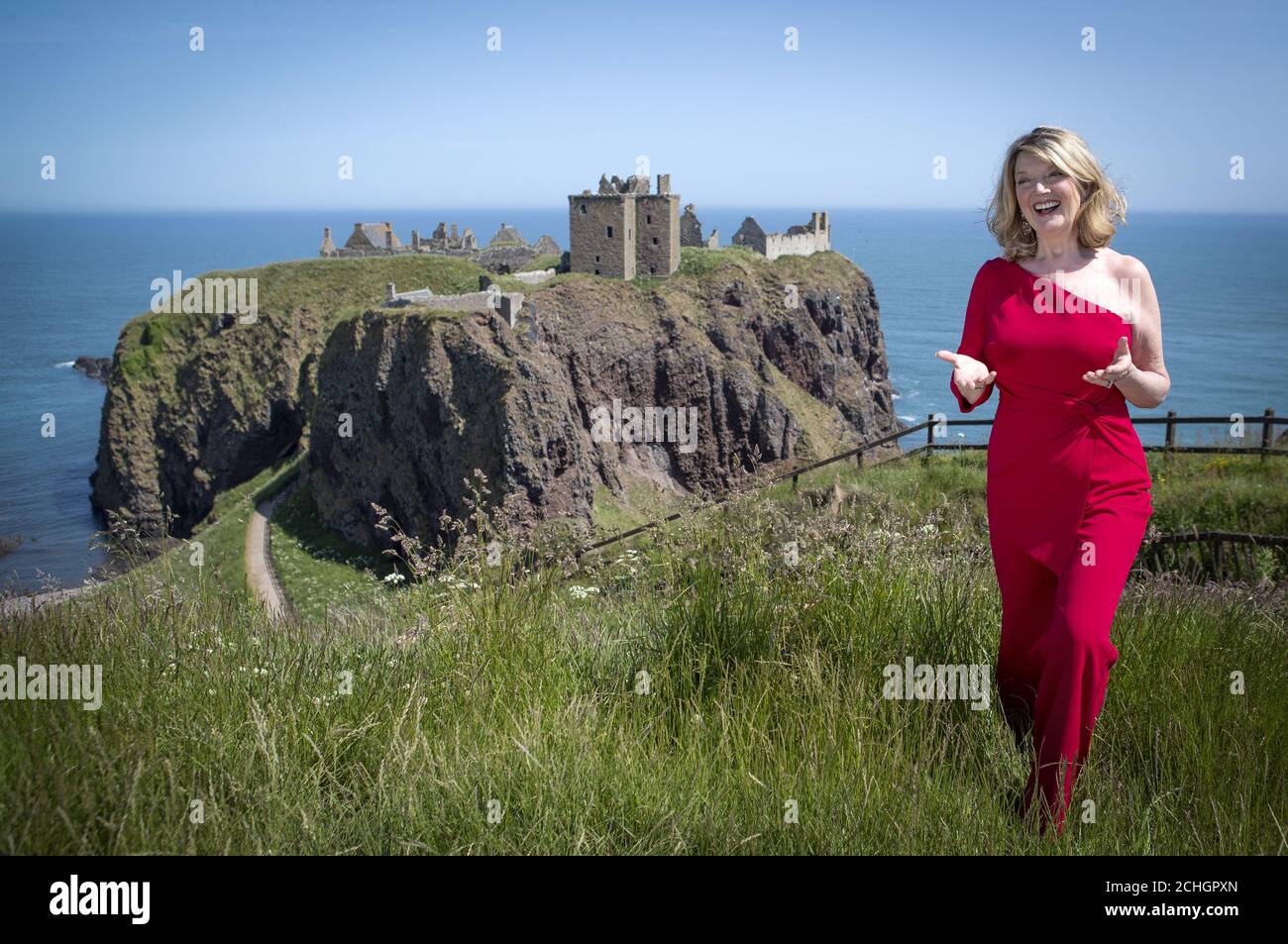 EMBARGOED TO 0001 MONDAY JUNE 29 Scottish singer, song-writer and broadcaster Fiona Kennedy sings 'Stronger for the Storm', a new international song of peace, on the clifftop overlooking Dunnottar Castle on the Aberdeenshire coast, at the launch of iSing4Peace on the anniversary of the signing of the Treaty of Versailles which brought an official end to the First World War and restored peace to the world. Stock Photo