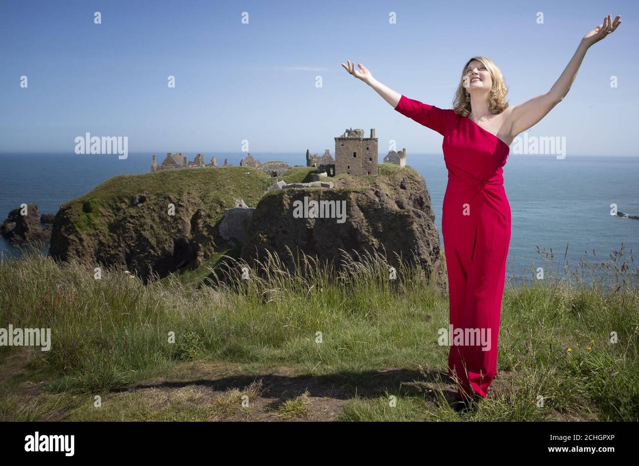 EMBARGOED TO 0001 MONDAY JUNE 29 Scottish singer, song-writer and broadcaster Fiona Kennedy sings 'Stronger for the Storm', a new international song of peace, on the clifftop overlooking Dunnottar Castle on the Aberdeenshire coast, at the launch of iSing4Peace on the anniversary of the signing of the Treaty of Versailles which brought an official end to the First World War and restored peace to the world. Stock Photo