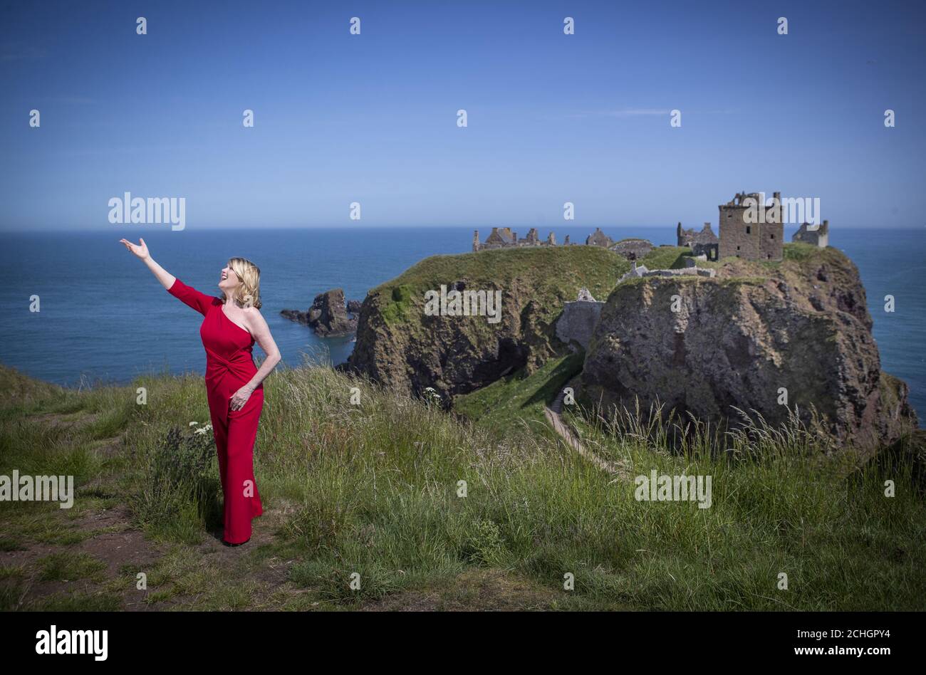 Scottish singer, song-writer and broadcaster Fiona Kennedy sings 'Stronger for the Storm', a new international song of peace, on the clifftop overlooking Dunnottar Castle on the Aberdeenshire coast, at the launch of iSing4Peace on the anniversary of the signing of the Treaty of Versailles which brought an official end to the First World War and restored peace to the world. Stock Photo