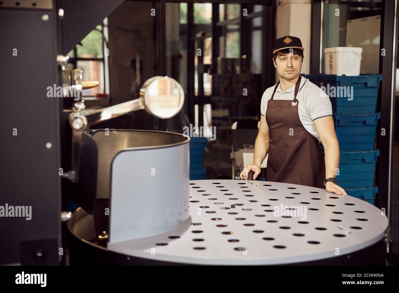 Handsome male worker using coffee roasting machine Stock Photo
