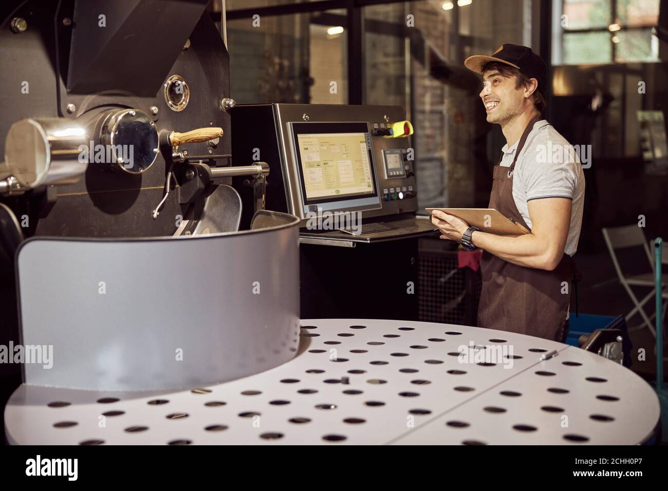 Cheerful young man using coffee roasting machine Stock Photo