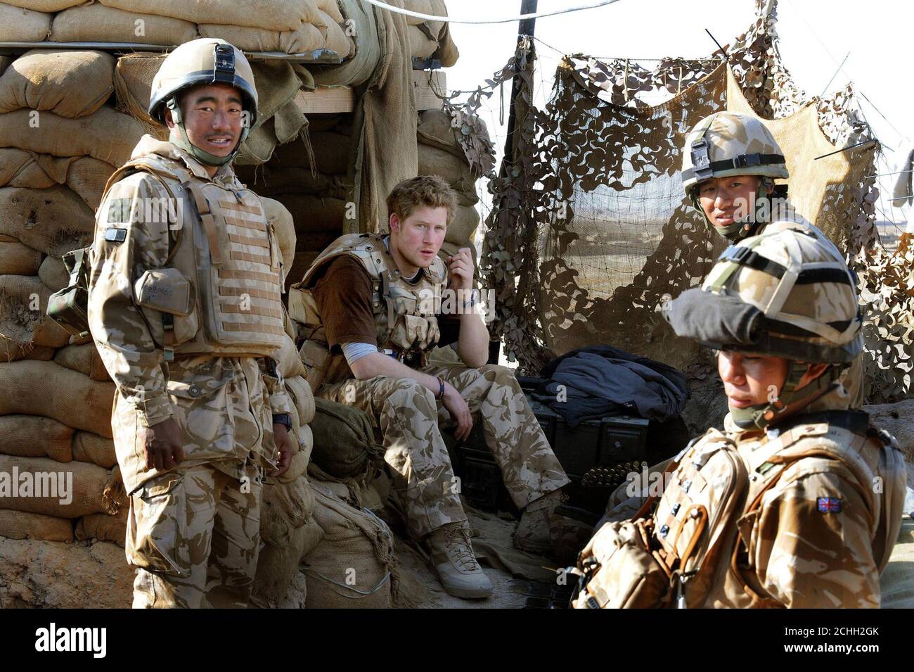 Prince Harry sits with Gurkha soldiers after firing a 50mm machine gun