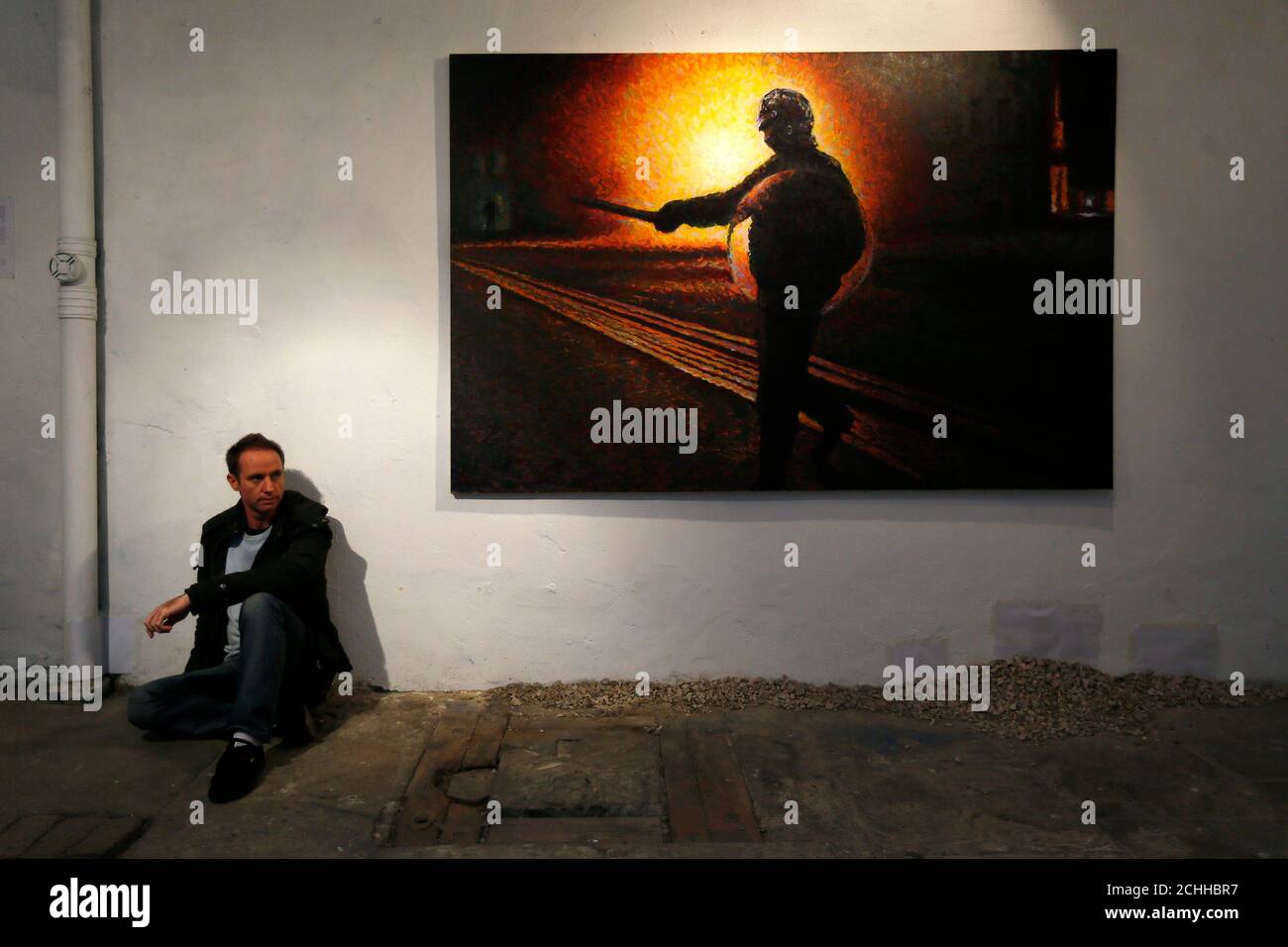 Street artist James Cochran, also known as Jimmy C, poses next to his spray painted picture 'Defy' at the Pure Evil Gallery in London October 10, 2013. The paintings were originally inspired by the London riots in 2011. REUTERS/Stefan Wermuth (BRITAIN - Tags: ENTERTAINMENT SOCIETY) Stock Photo