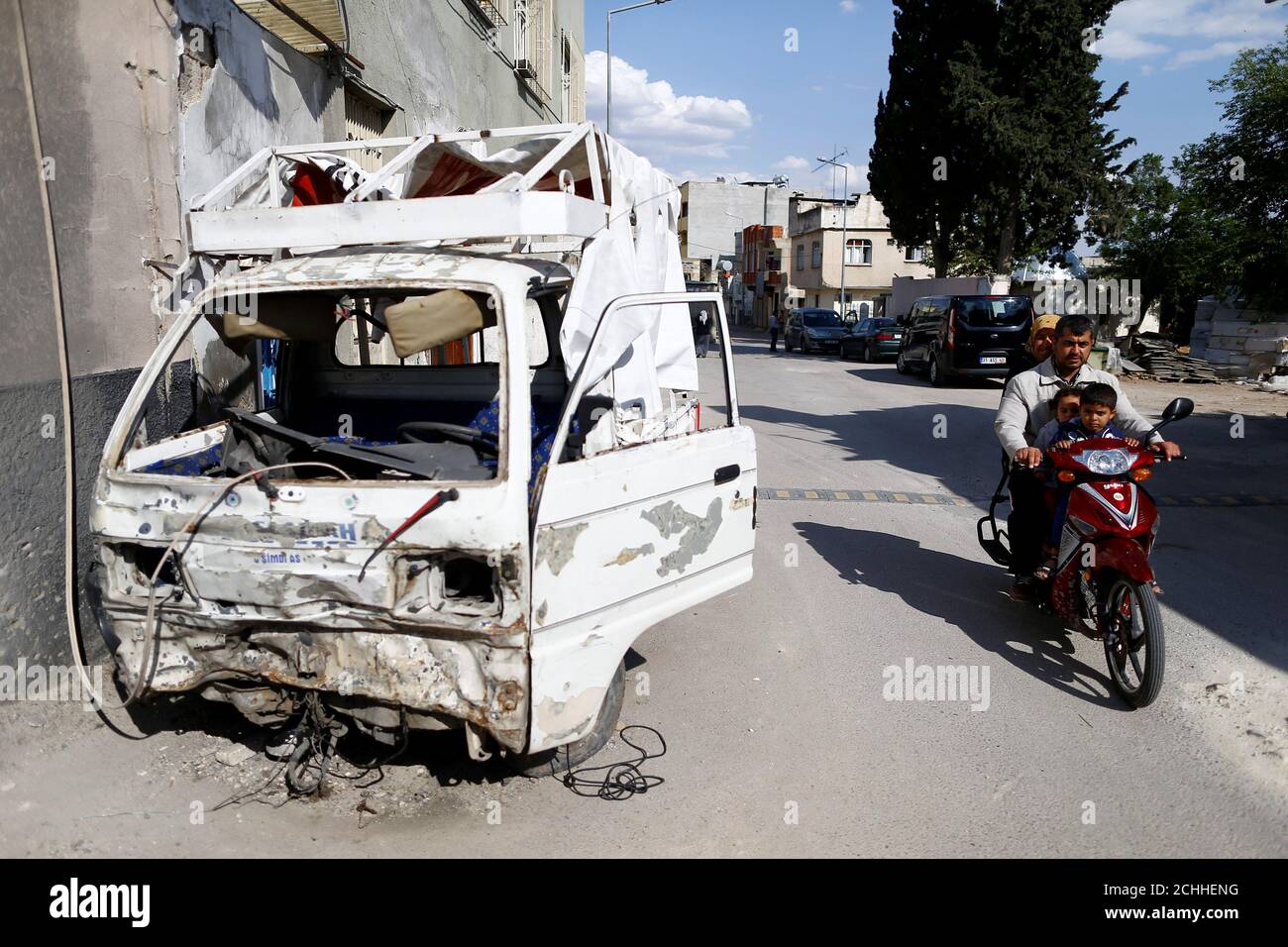 A man rides a motorcylce past a vehicle hit by rocket fire from Syria in Turkey's southeastern border town of Kilis May 10, 2016. REUTERS/Osman Orsal Stock Photo