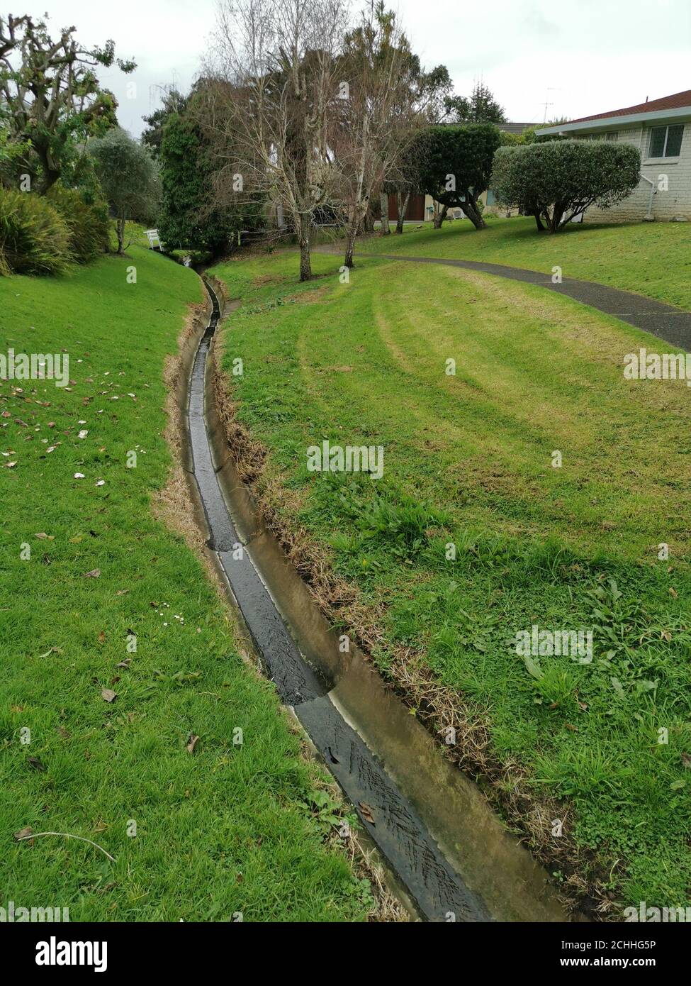 Vertical landscape view with a small stream of water flowing inside a ditch Stock Photo