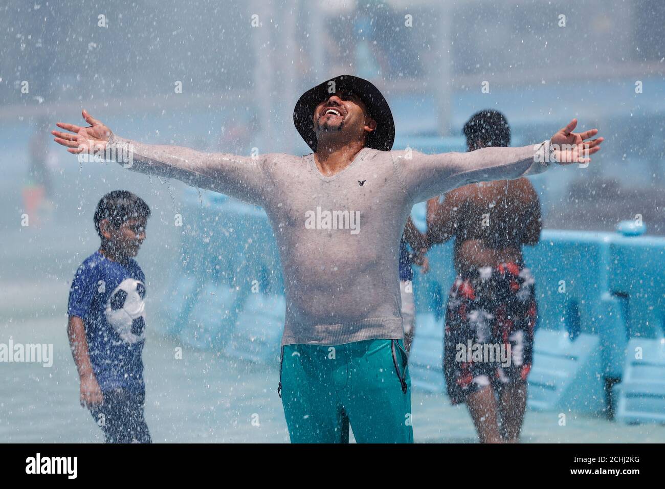 A man enjoys the water in the Unisphere at Flushing Meadows Park in the Queens borough of New York City, U.S., July 9, 2019.  REUTERS/Shannon Stapleton Stock Photo