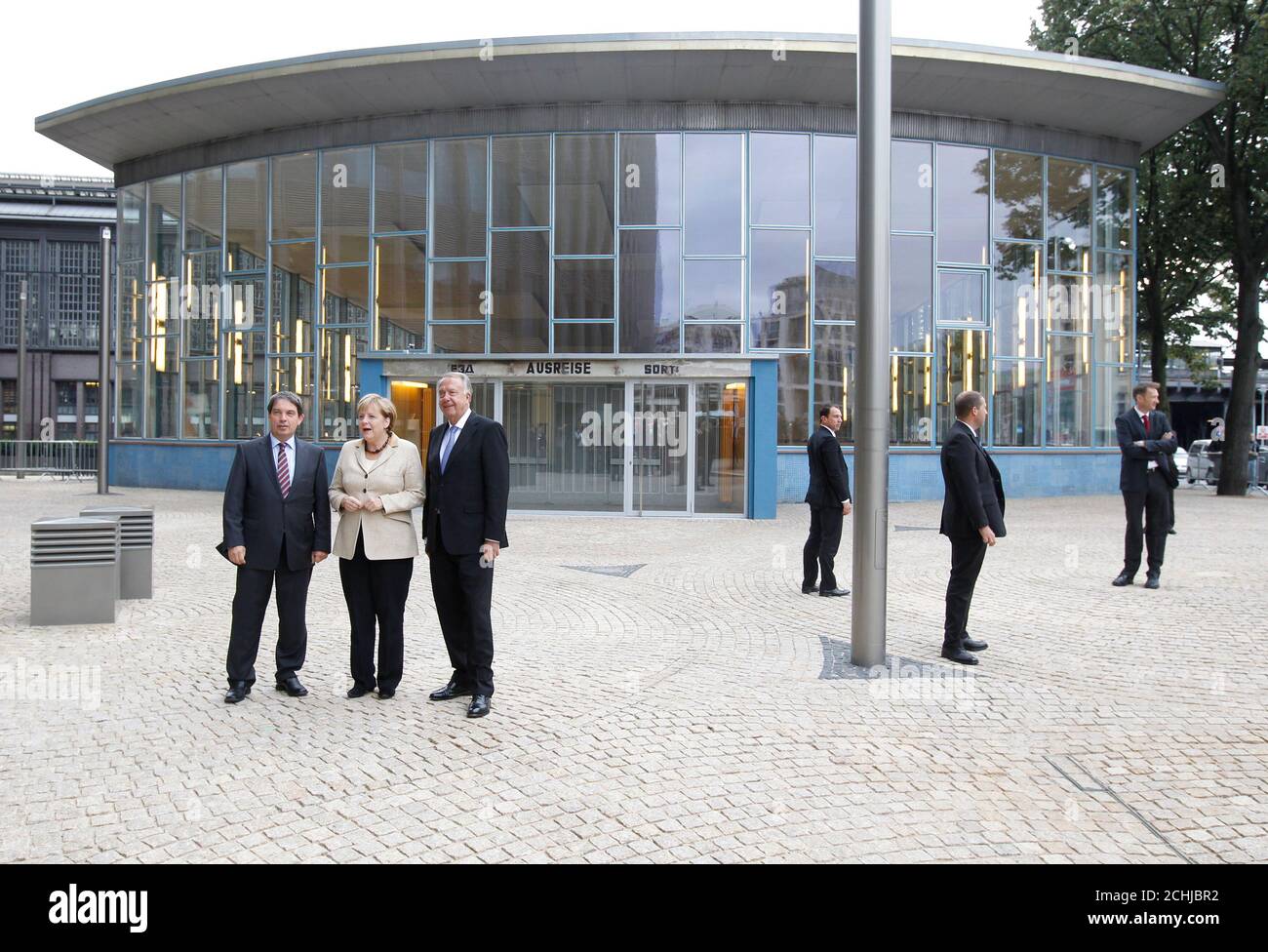 German Chancellor Angela Merkel (2nd L), Culture State Minister Bernd Neumann (3rd L) and the director of the House of the History of Germany foundation, Hans Walter Huetter (L), pose outside the former Traenenpalast (Palace of Tears) East German border crossing station during the opening of the 'Grenzerfahrung' (Border experiences) exhibition in Berlin, September 14, 2011.  The building at Berlin's Friedrichstrasse station earned its colloquial name among Berliners because of the many tearful scenes that took place outside its doors during the years of Germany's division.   REUTERS/Thomas Pet Stock Photo