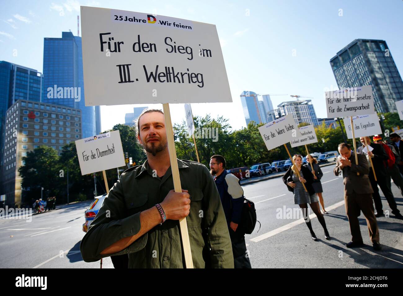 People take part in a protest in Frankfurt, Germany, October 3, 2015, as Germany's political leaders celebrate the country's 25th anniversary since the reunification of East and West Germany. The texts read 'For the stupidity', 'For the victory in World War Three', 'For real love'.   REUTERS/Kai Pfaffenbach Stock Photo