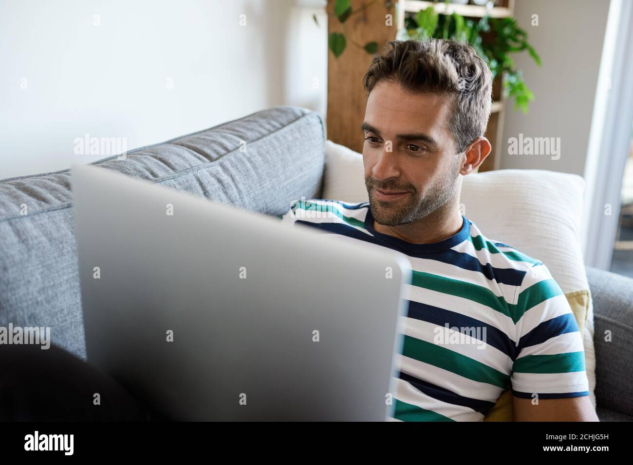 Young man relaxing on his sofa using a laptop Stock Photo