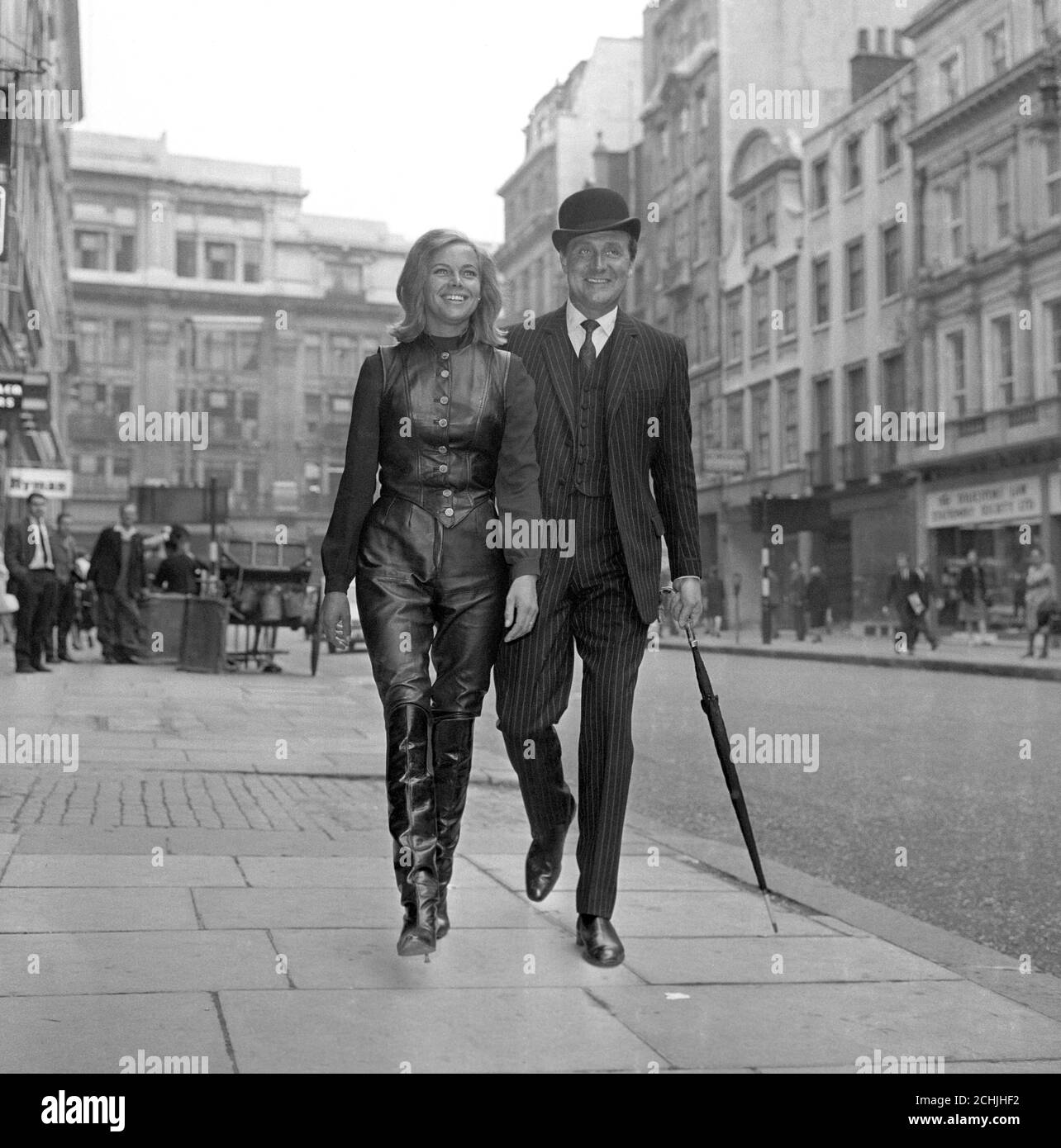 HONOR BLACKMAN (CATHERINE GALE), OF THE ATV THRILLER SERIES 'THE AVENGERS' TYPIFIES THE PIN UP GIRL OF CONTEMPARY BRITAIN. SHE IS THE SYMBOL OF THE JET AGE WOMAN, WITH LEATHER JERKIN, BREECH & HIGH BOOTS. HERE WITH PATRICK MaCNEE AS THEY ARRIVE AT SELBYS RESTAURANT. Stock Photo