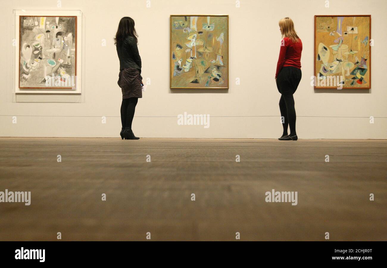 Visitors look at (left to right) 'The Betrothal I, II and III', a triptych of paintings which is part of the new exhibition 'Arshile Gorky: A Retrospective' at Tate Modern, London. Stock Photo