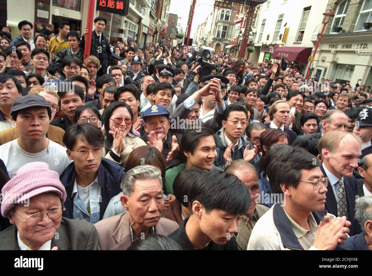 Crowds gather in front of a large television screen in London's China Town to watch the historic moment live as Britain officially handed over Hong Kong to China. Stock Photo