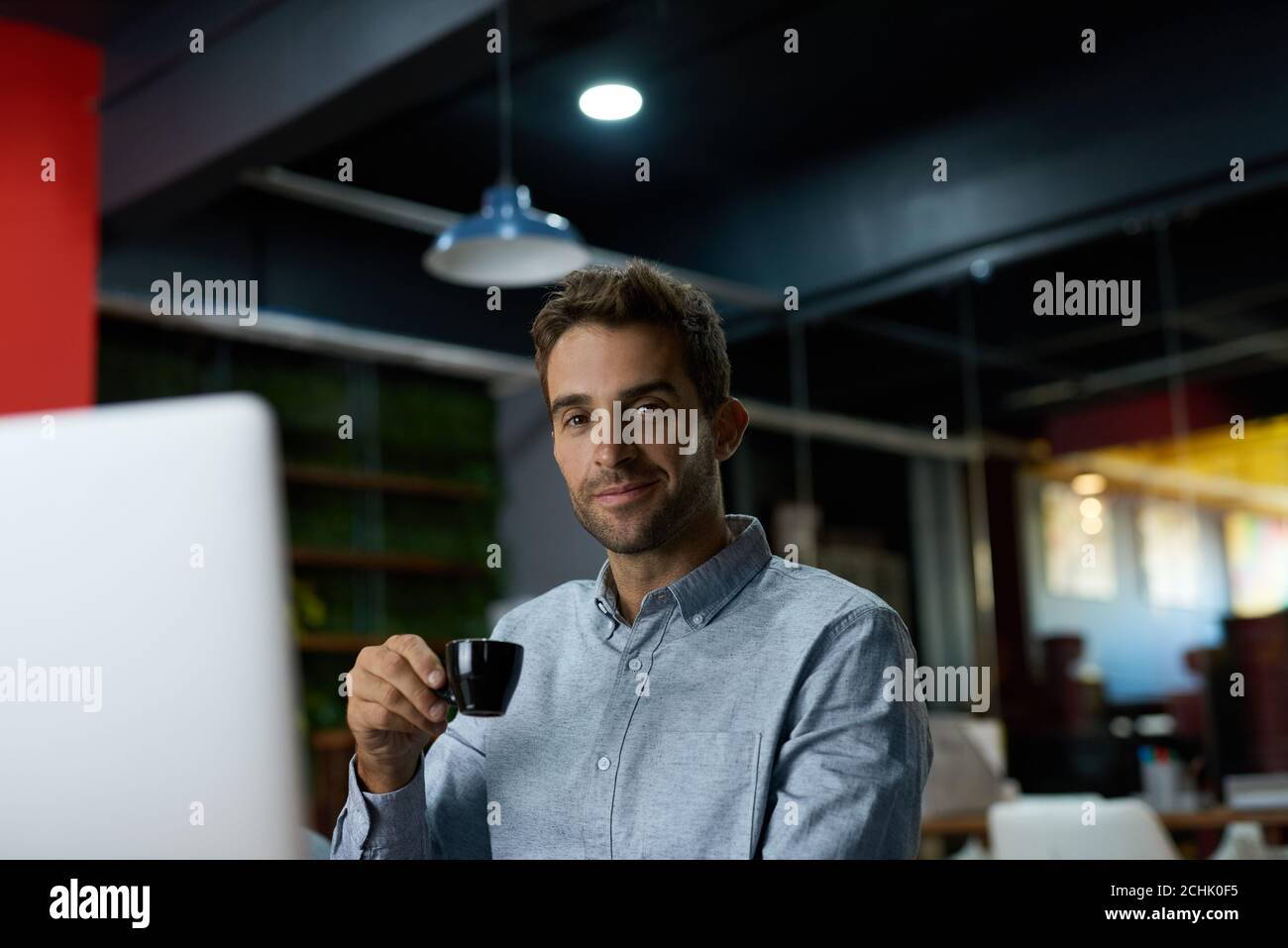 Young businessman drinking coffee while working at his desk Stock Photo