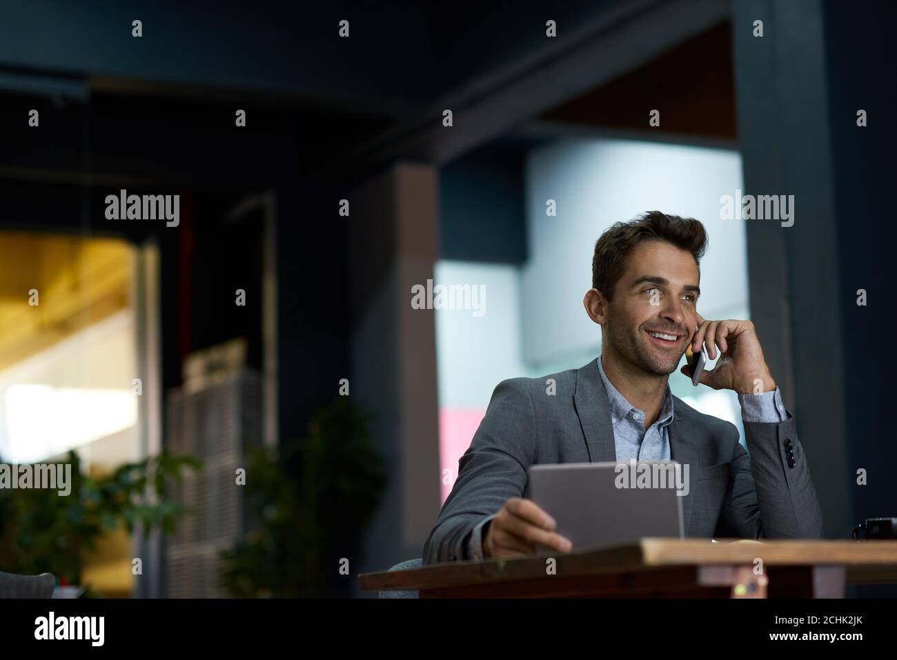 Smiling businessman using a tablet and talking on his cellphone Stock Photo