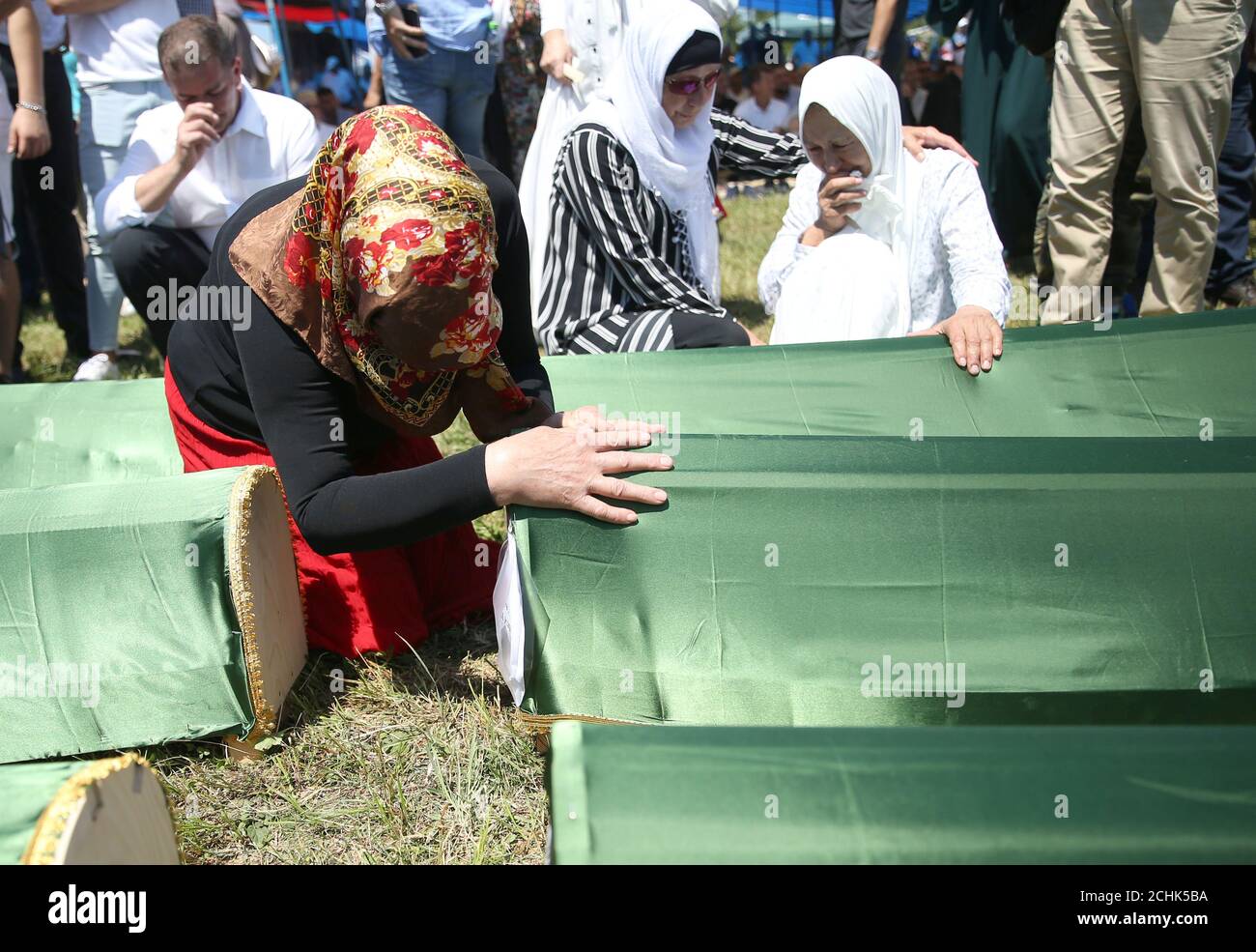 Bosnian Muslim women touch the coffins during a mass funeral in the