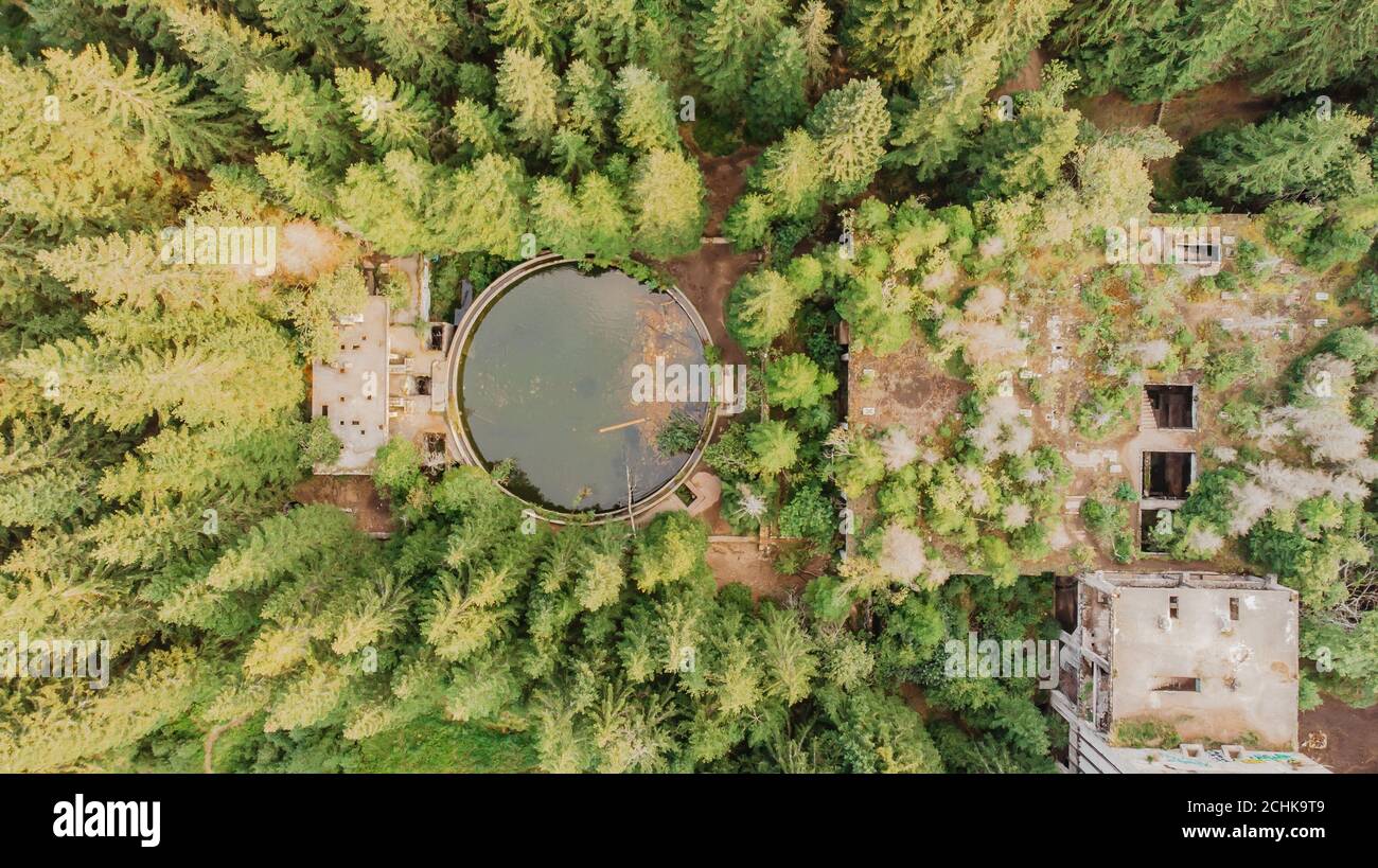 Top aerial view of abandoned water reservoir,tank, and buildings of old tin mine in Rolava,Ore mountains,Czech Republic. Beautiful nature from above. Stock Photo