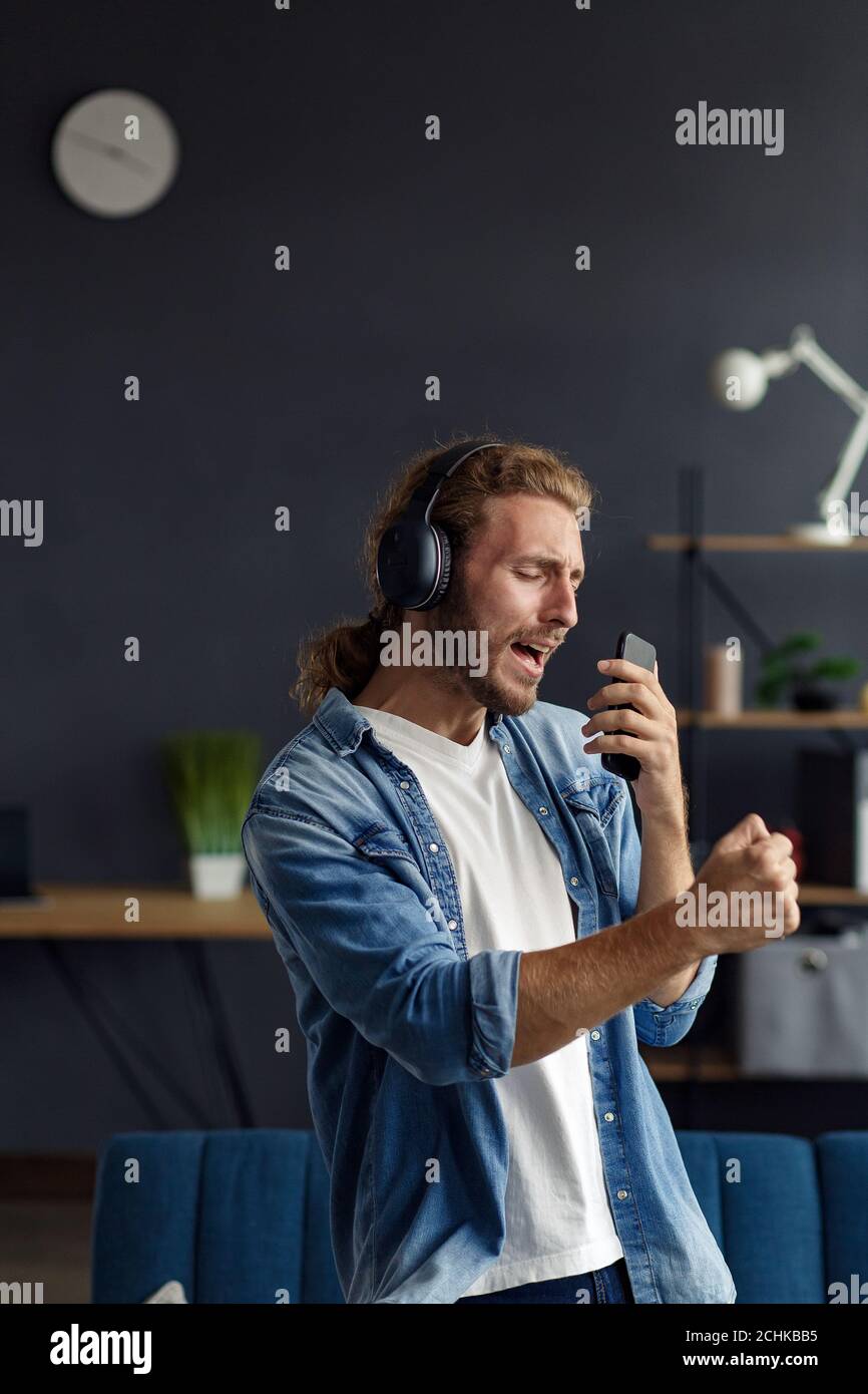 Handsome long haired curly man with headphones listening music