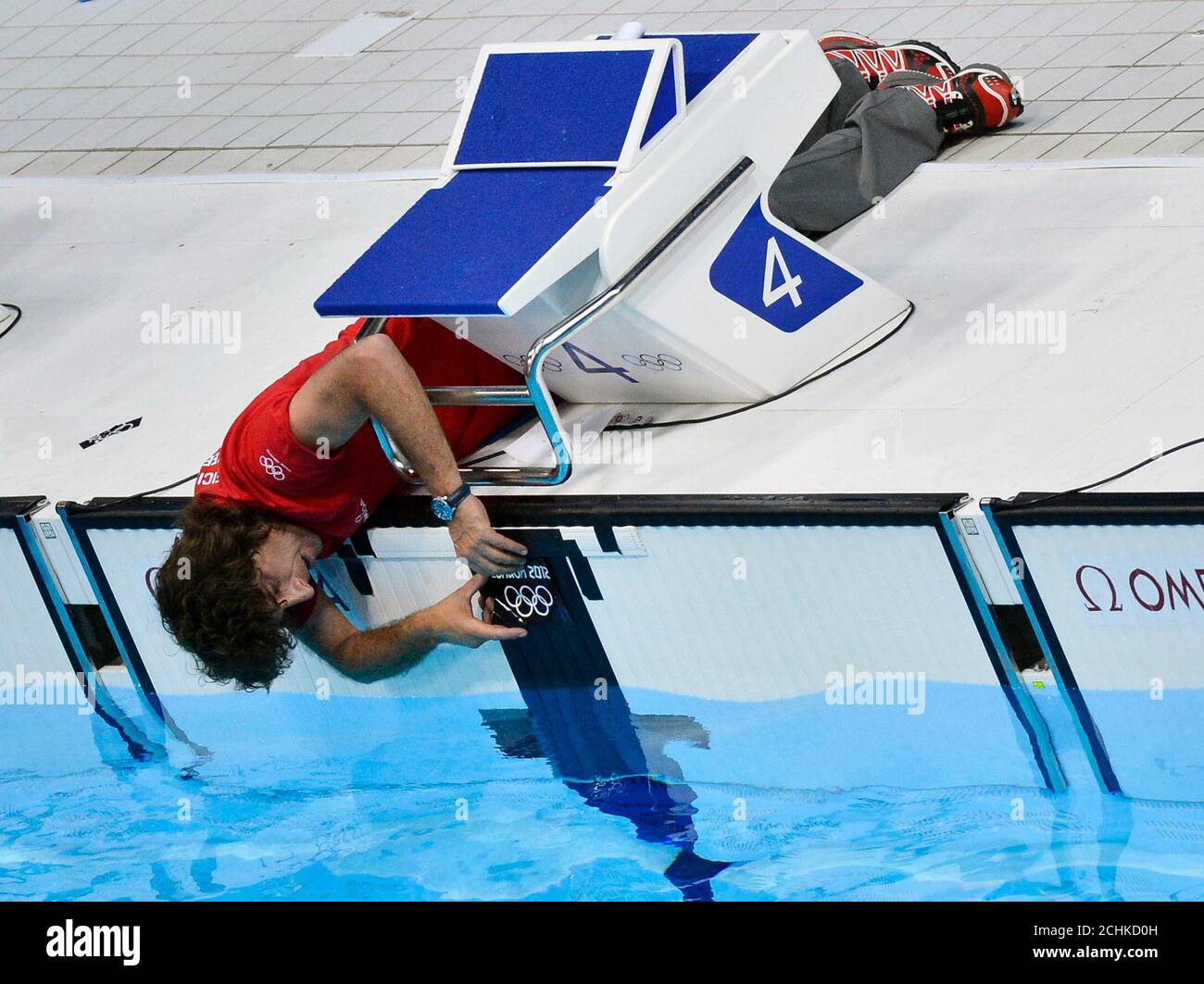 A Technician Attaches A Sticker Bearing The Rings Of The Olympic Logo On The Wall Of A Pool Lane At The Main Pool Of The Aquatics Centre Before The Start Of The