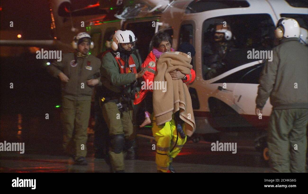 A still image taken from a video shows a rescue worker carrying a children,  rescued from the Hotel Rigopiano, as they arrive by helicopter in the city  of Pescara, Italy January 20,