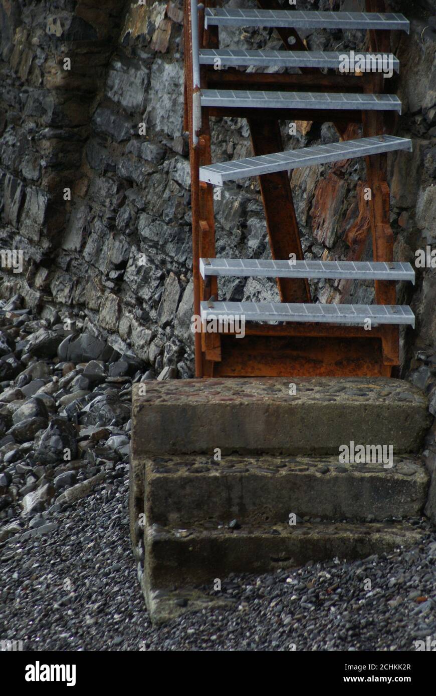 Vertical shot of a rusty and damaged ladder on the stone wall Stock