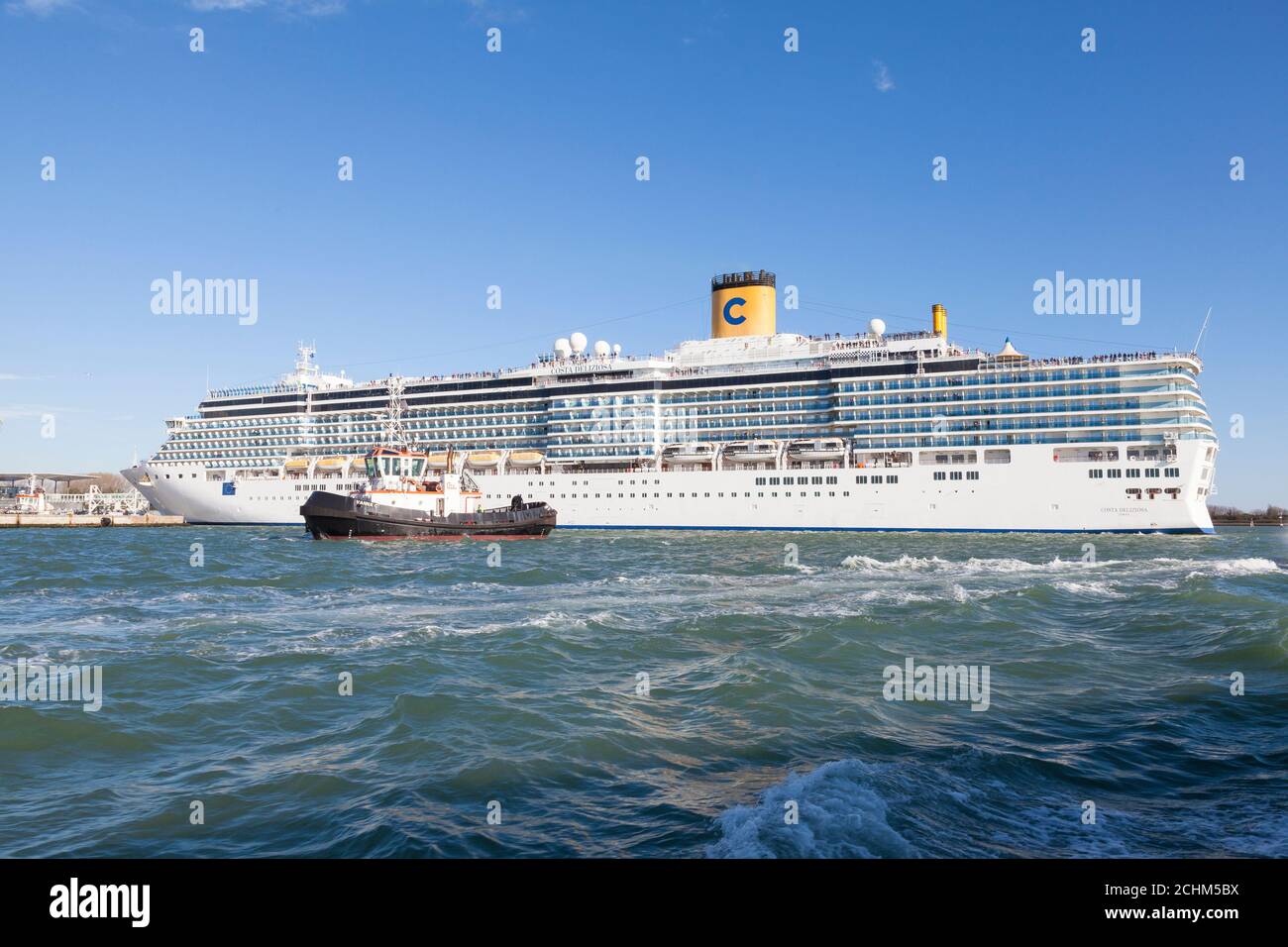 Costa Delizioza Passenger Liner or cruise ship  of Costa Crociere departing Venice , Italy with tug and passengers standing on deck on a sunny summer Stock Photo