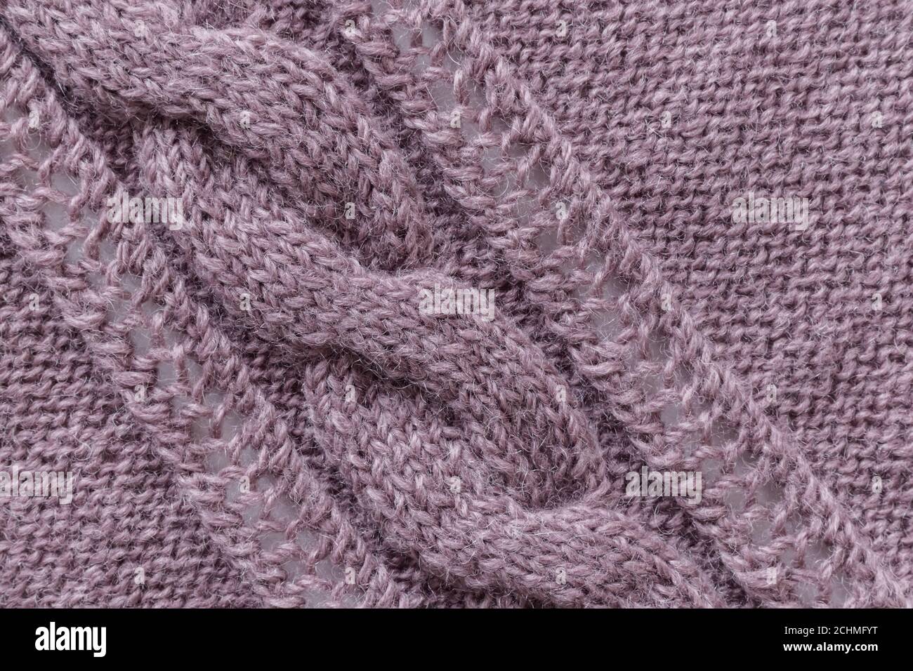 Openwork pattern knitted with needles from pink wool yarn. Stock Photo