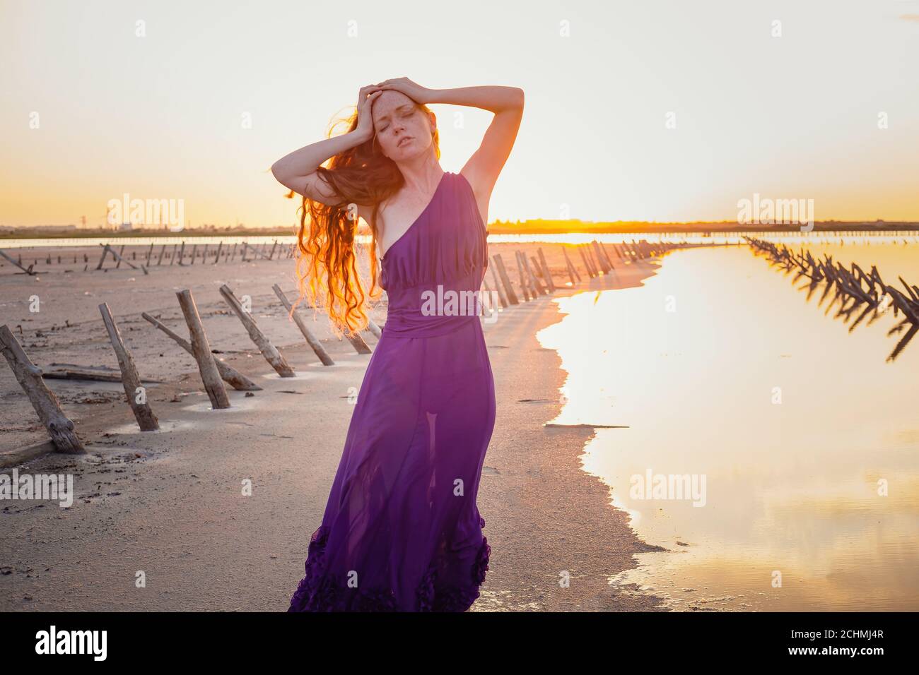 Elegant woman in silky purple dress walking by a salt lake. Romantic ...