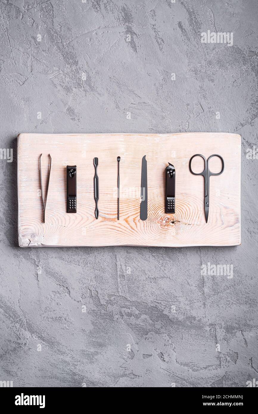 Set of manicure, pedicure tools and accessories on wooden board, stone concrete background, top view Stock Photo