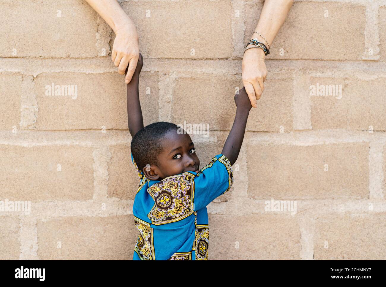 Handsome African Black Boy Holding Hands with White Caucasian Woman Volunteering in Africa Stock Photo