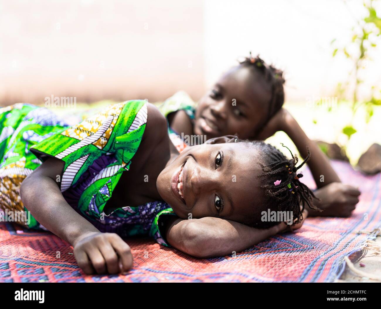 Smiling African Sisters Lying on Floor Smiling, Laughing Cheerful at the Camera Stock Photo