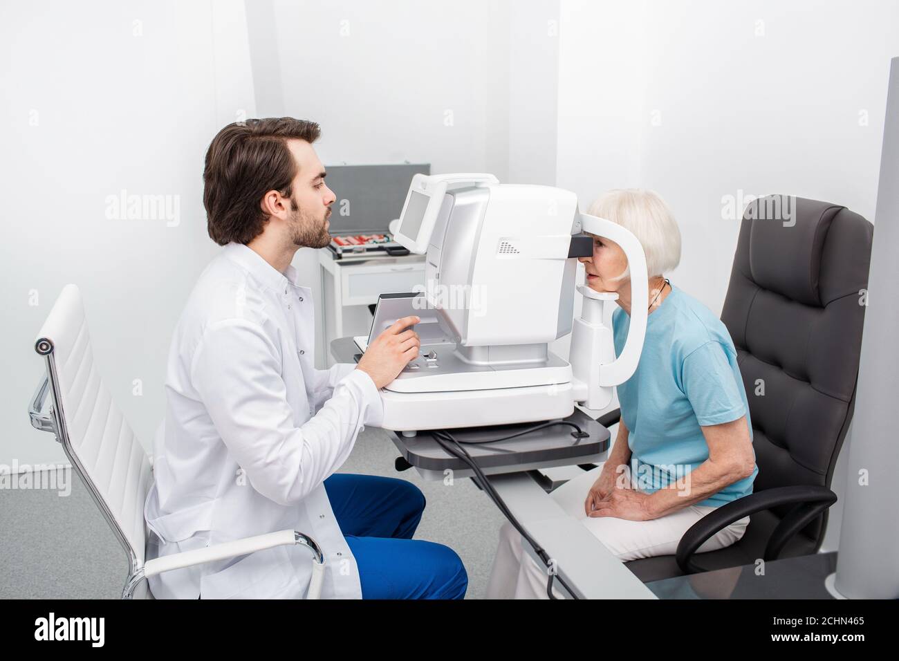 Concentrated optometrist checking eye for a patient using modern equipment. Eye exam and vision diagnostic Stock Photo