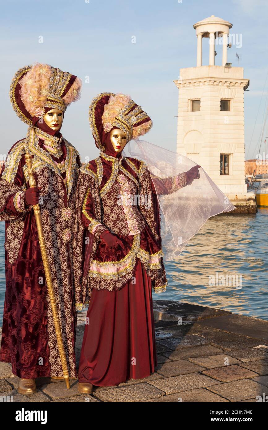 Venice, Veneto, italy - couple in costume at the Venice Carnival at sunset  posing with the lighthouse at San Giorgio Maggiore behind them Stock Photo  - Alamy