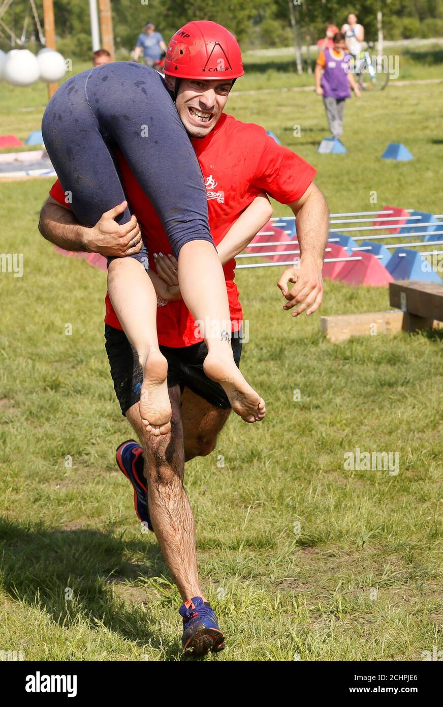 A man carries his wife while racing in the Wife Carrying competititon to mark the City Day in Krasnoyarsk, Russia June 10, 2018. REUTERS/Ilya Naymushin Stock Photo