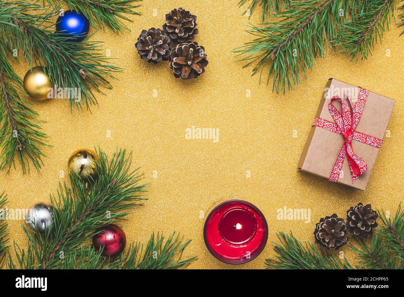 Golden Christmas background with pine tree branches and holiday decorations. Still life. Bright yellow flat composition. Celebration frame border, moc Stock Photo