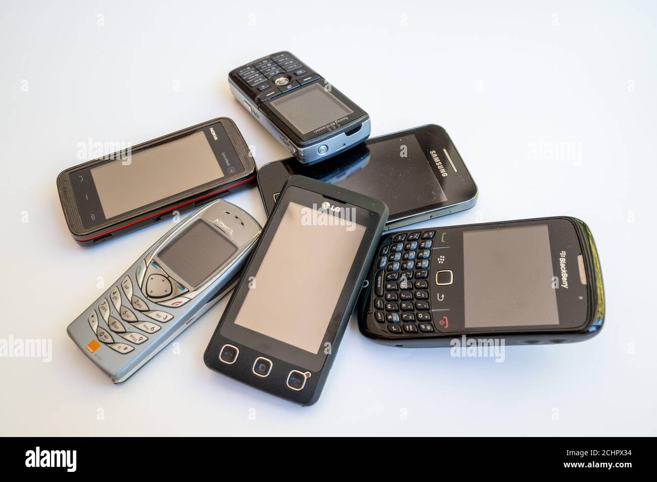 A selection of old mobile phones in a pile on white background. Stock Photo
