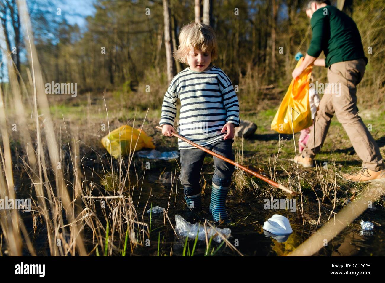 Father with small kids collecting rubbish outdoors in nature, plogging concept. Stock Photo