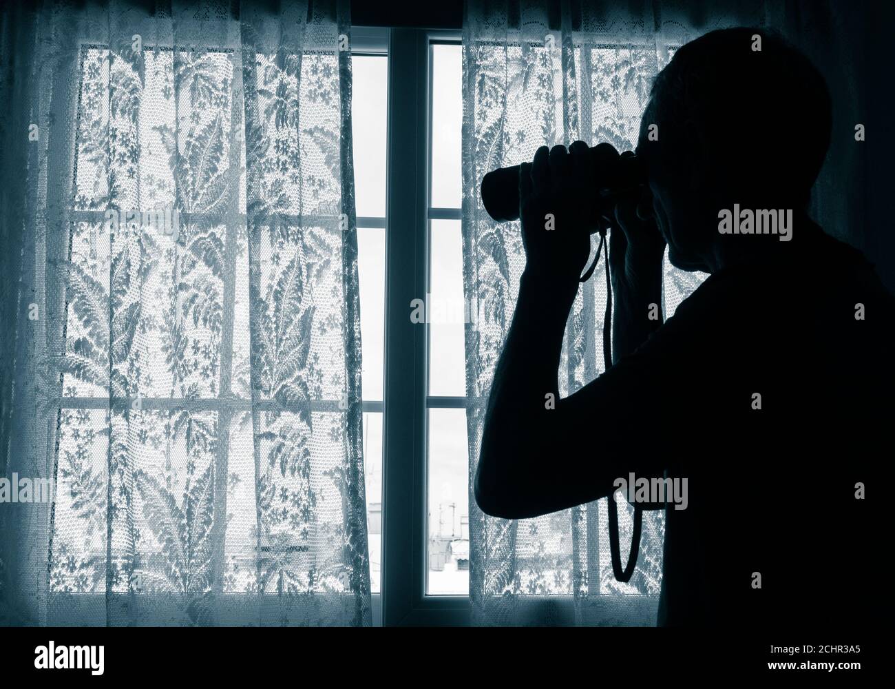 Man with binoculars looking out of window from behind net curtain: nosey neighbour, spy, undercover cop, pervert, stalker... concept Stock Photo