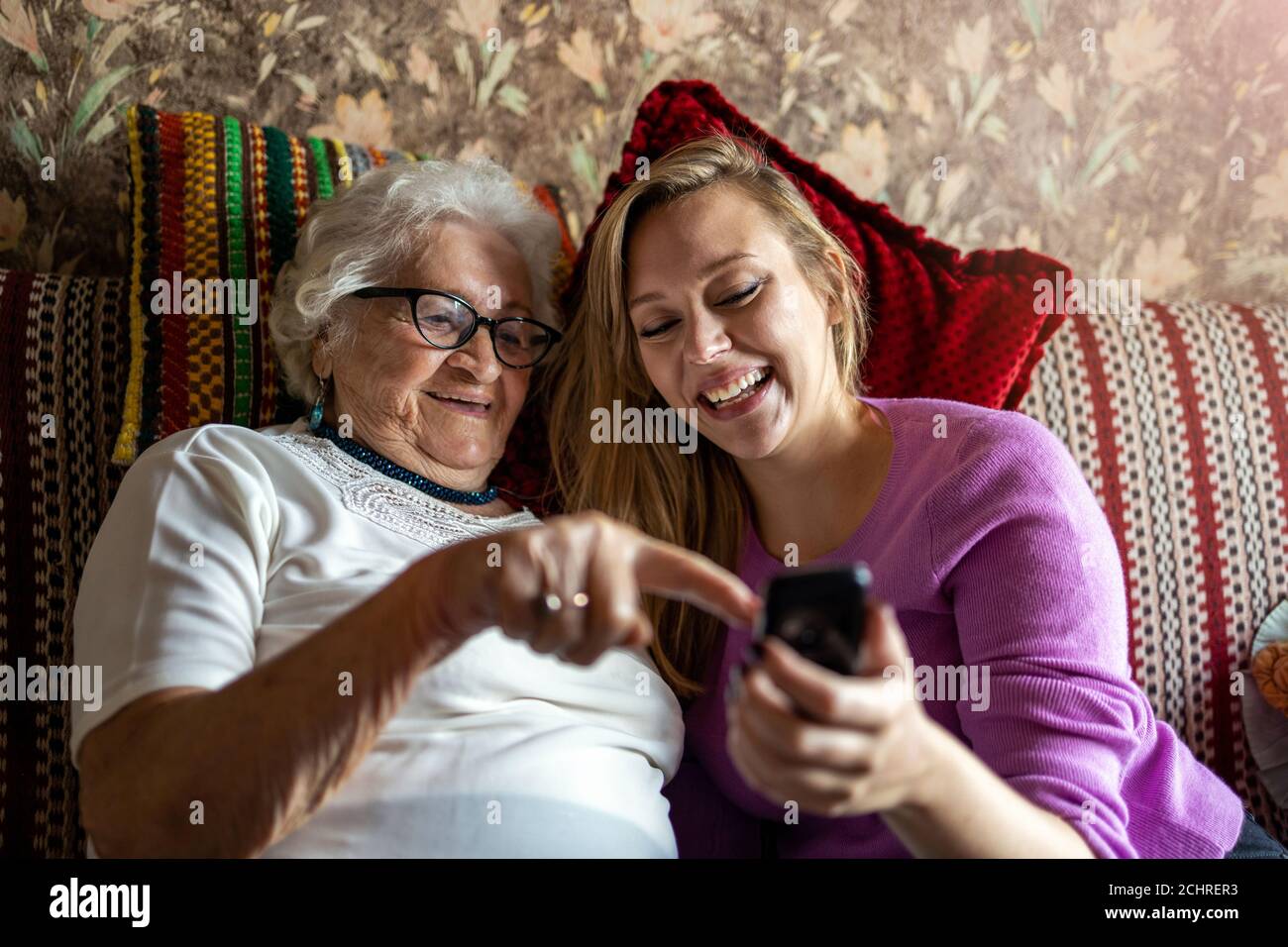 Senior woman and her adult granddaughter using smartphone together Stock Photo