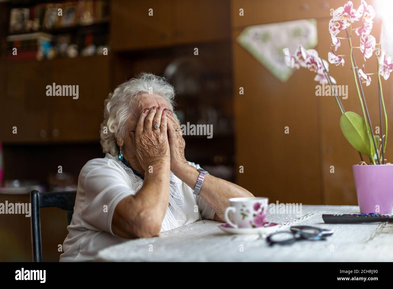 Senior woman holding head in hands in despair Stock Photo
