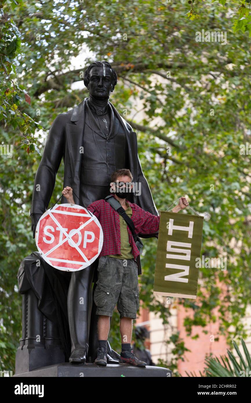 Protester holding placards beside statue during HS2 Rebellion tree occupation, Parliament Square, London, 5 September 2020 Stock Photo