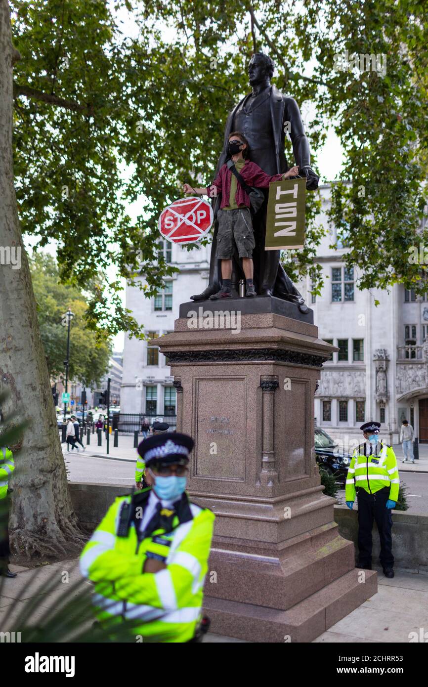 Protester holding placards beside statue during HS2 Rebellion tree occupation, Parliament Square, London, 5 September 2020 Stock Photo