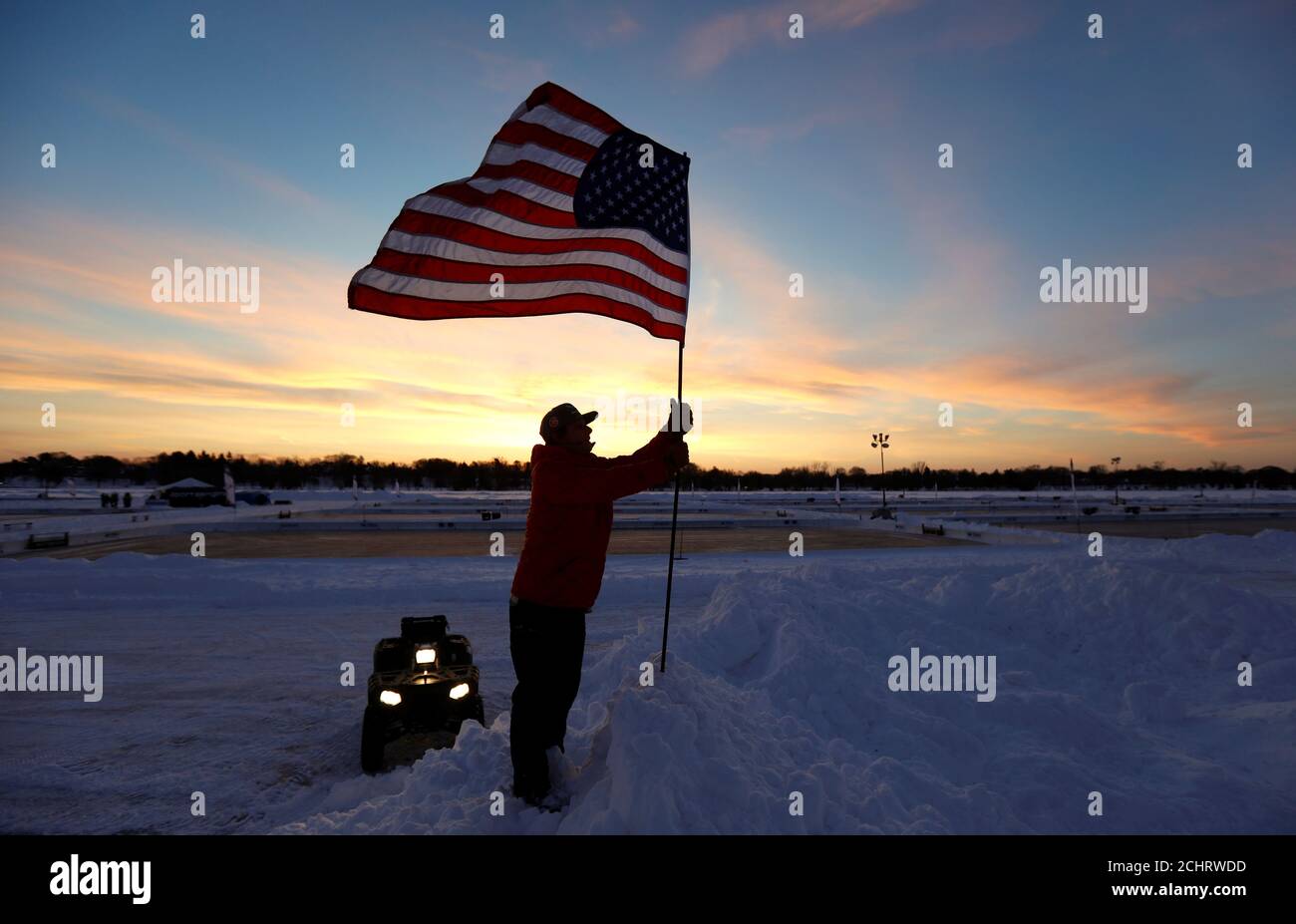 A flag is raised at sunrise for the U.S. Pond Hockey Championships on Lake Nokomis in Minneapolis, Minnesota, U.S. January 26, 2018. Picture taken January 26, 2018.   REUTERS/Kevin Lamarque Stock Photo